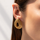 Gold hoop earring worn by a person with a neutral background